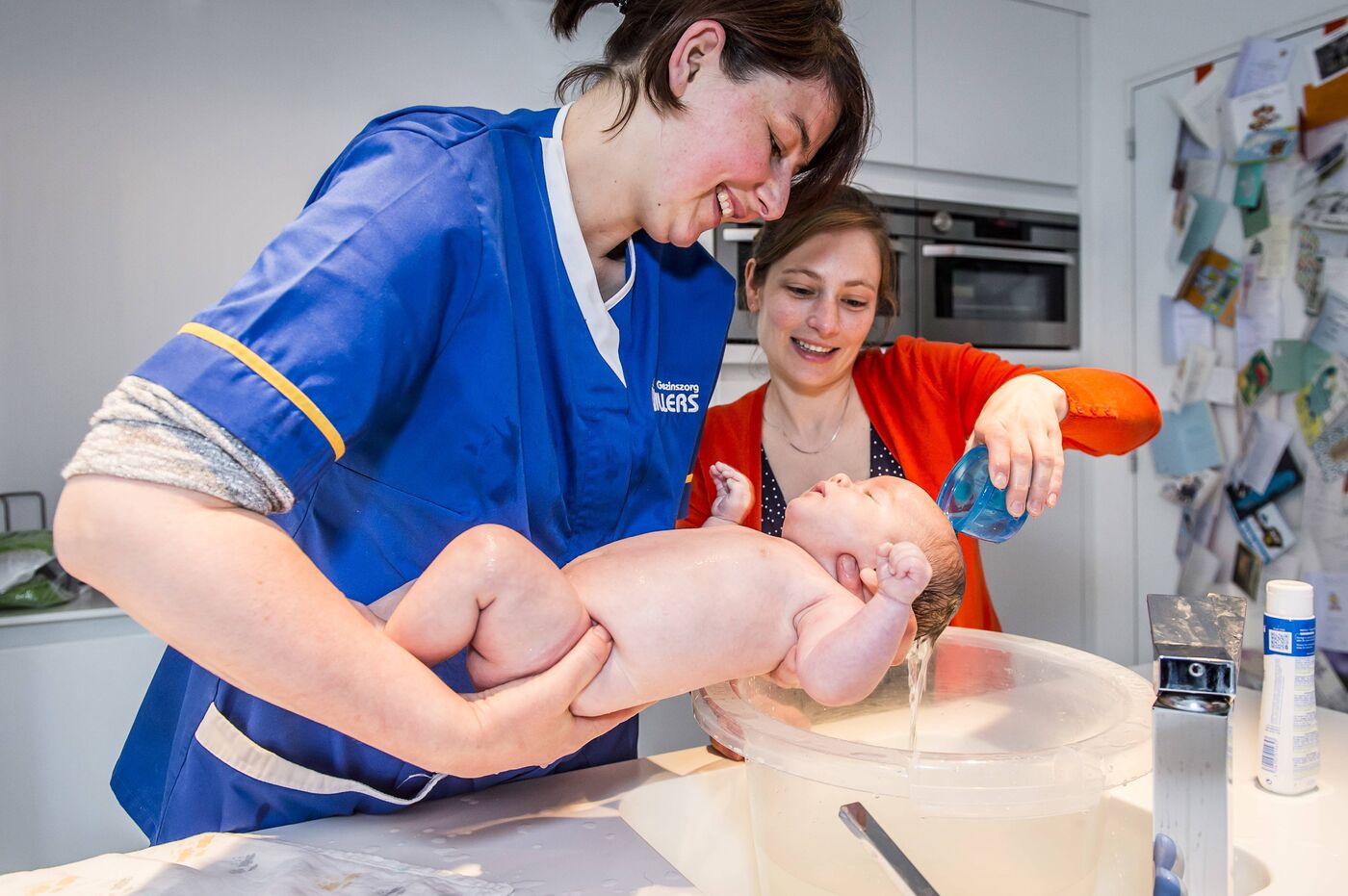 Verzorgende geeft baby een bad