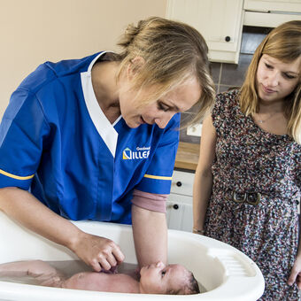 Verzorger geeft baby een bad